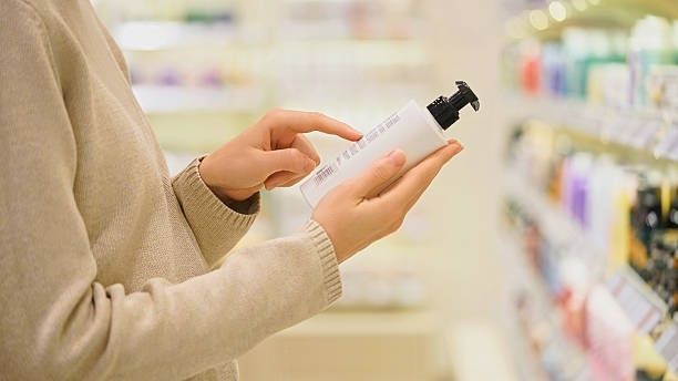Person prüft in einer Drogerie das Etikett einer Kosmetikflasche